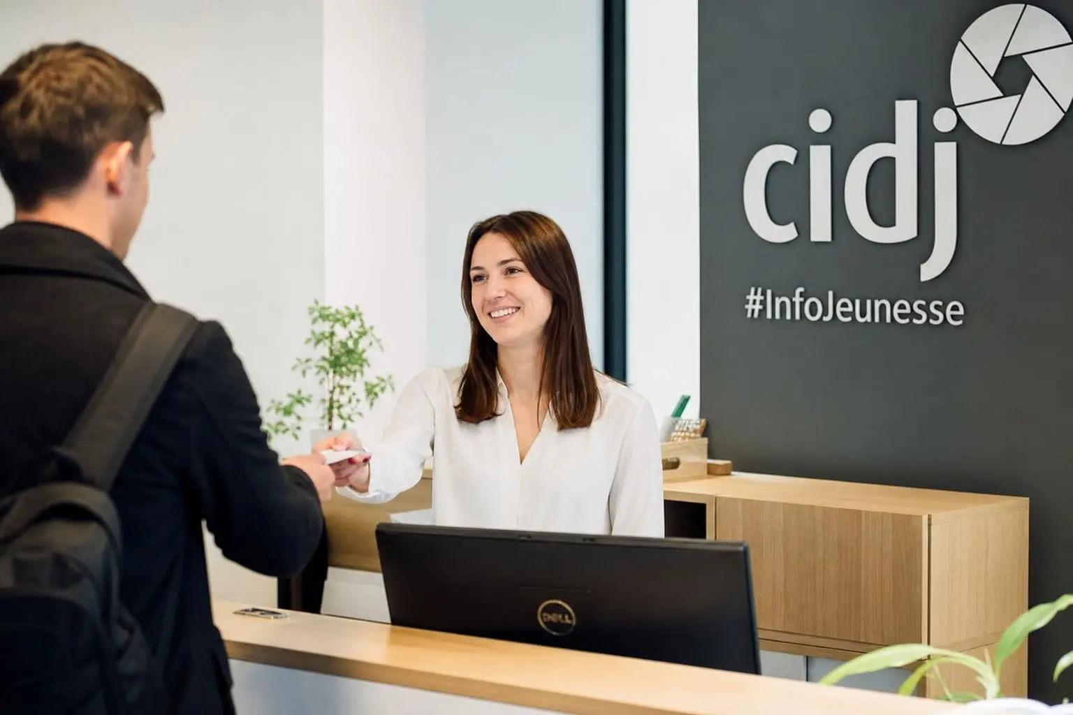 Accueil d’un salarié lors du processus d’intégration, avec une hôtesse souriante derrière un comptoir.